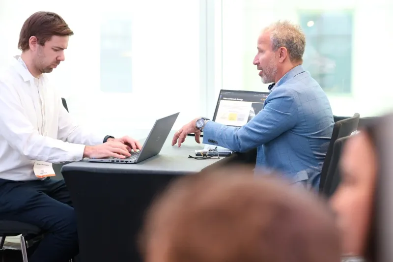 Two mining industry professionals discussing opportunities across a table with laptops