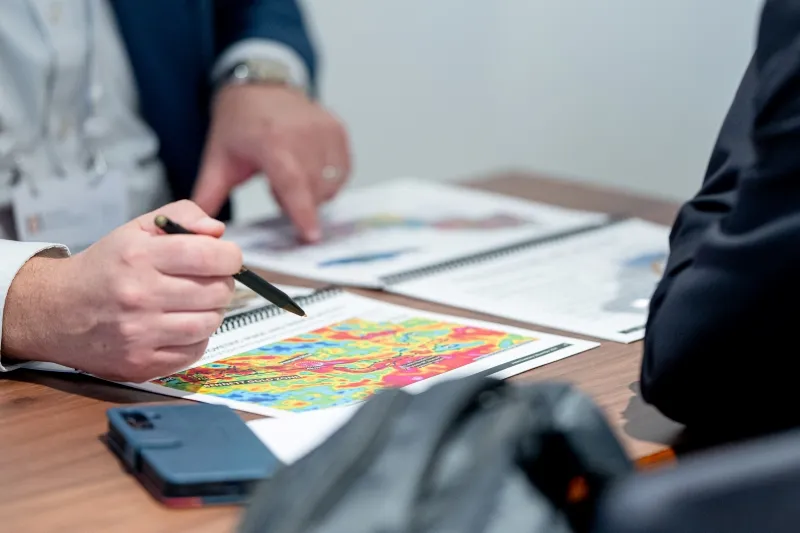 Mining industry professionals reviewing project maps during a private meeting