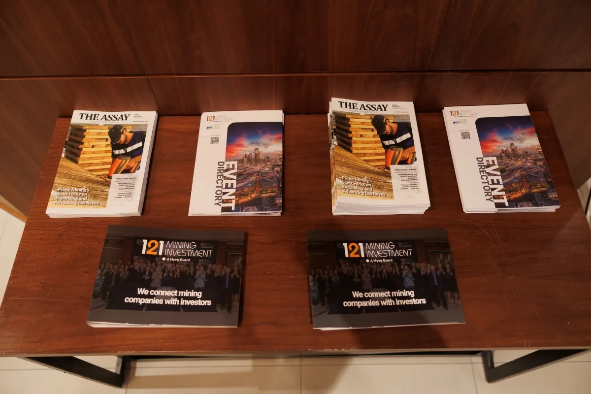 Stacks of The Assay magazines, event directories and 121 Mining Investment brochures on display