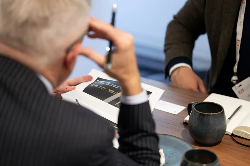 Mining industry professionals reviewing printed company information during a private meeting